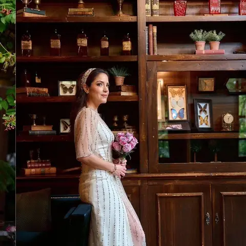Novia con su ramo junto a una biblioteca de madera