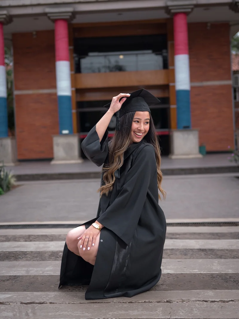 Graduada levantando su diploma frente a la facultad
