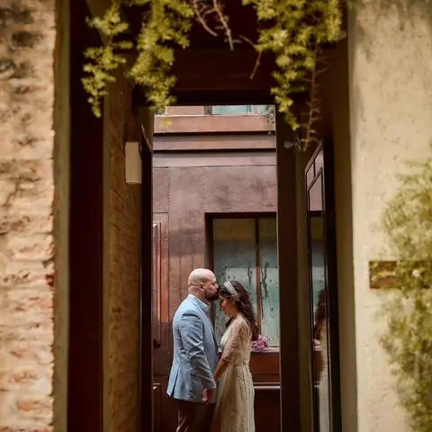 Pareja abrazada bajo un arco antiguo con plantas